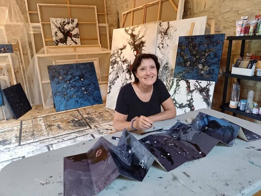 Odile CARITEAU in the Studio: Dans le petit atelier en 2021, avec un livre accordéon dans les tons bleus.