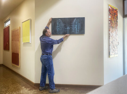 Malcolm Koch in the Studio: Arranging artwork on exhibit in the studio gallery
