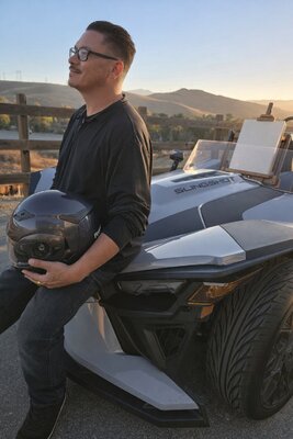 Ryan Beal in the Studio: My studio in its most natural form—outdoors, mobile, and part of everyday life. I’m leaning against my Polaris Slingshot with an easel in the passenger seat, reflecting a practice that moves with inspiration rather than remaining fixed.