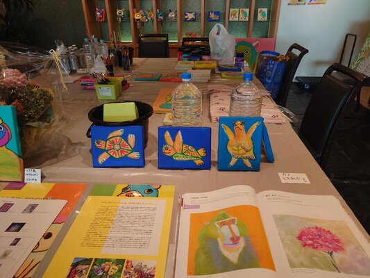 SAORI TRIBE in the Studio: A view of my temporary studio during an artist-in-residence program at a hotel. This is the live creative space where I bring my vibrant characters to life in an open, light-filled environment.